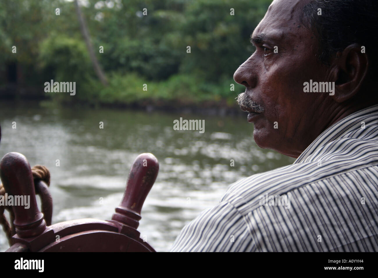 Portrait of a man steering a house boat on the backwaters of kerala in india Stock Photo