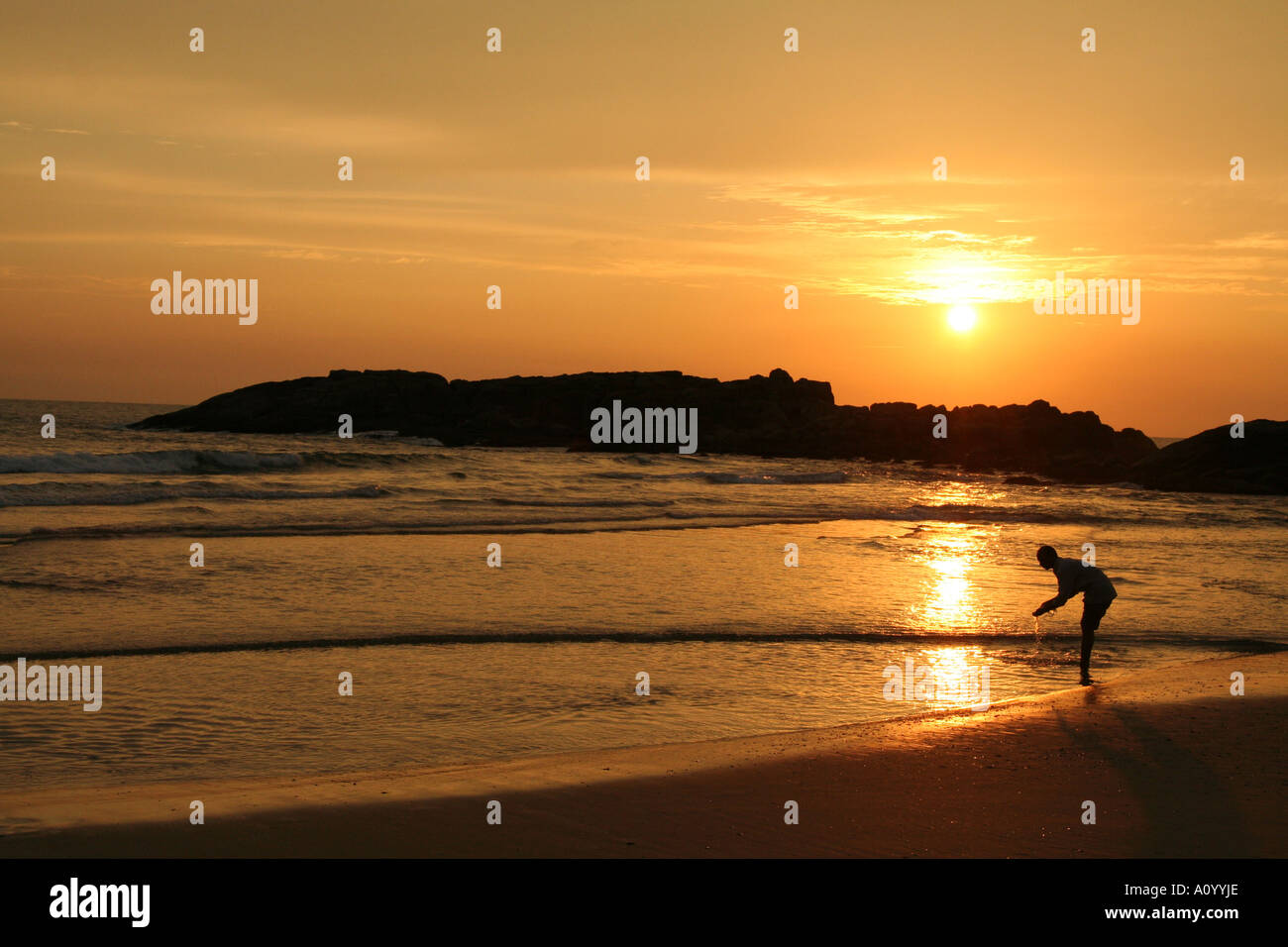 Man washing on Kovalam beach alone at sunset Stock Photo