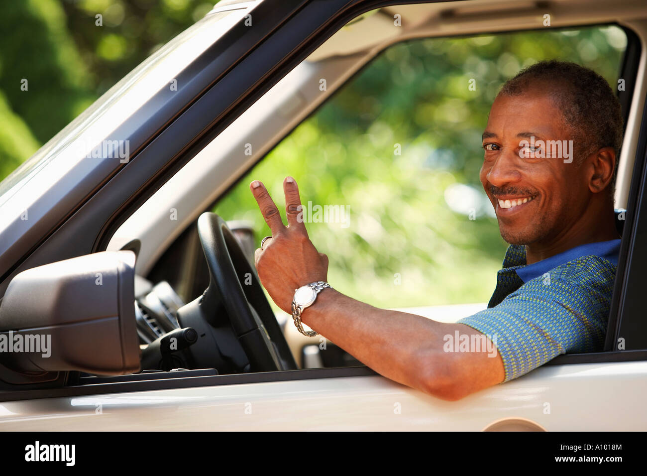 Middleaged African man flashing the peace sign while driving Stock