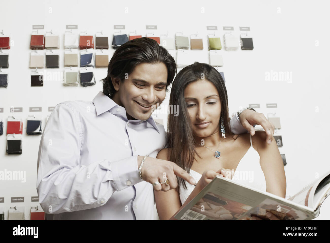 Close-up of a young couple choosing fabric swatches from a magazine Stock Photo