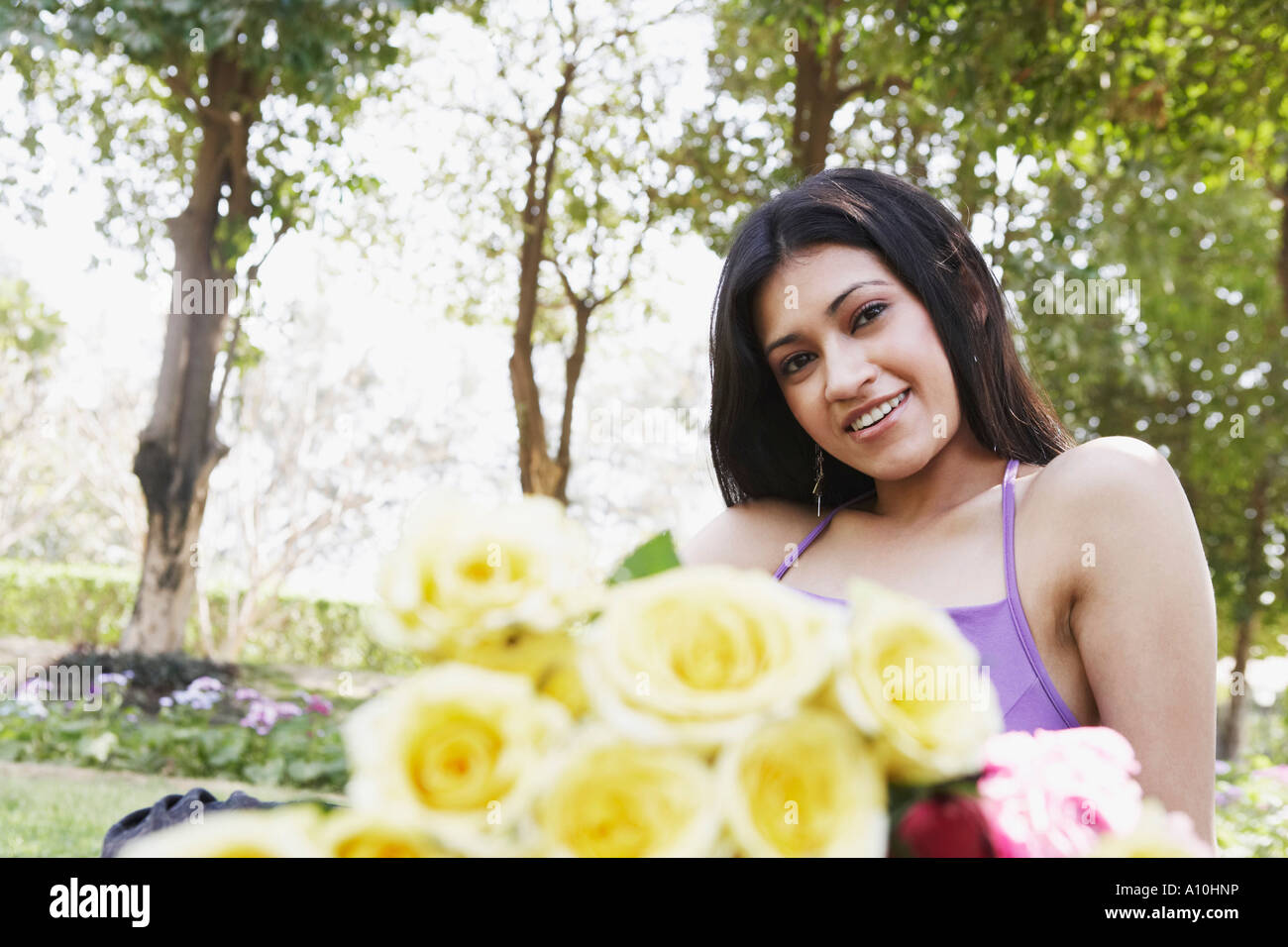 Portrait of a young woman sitting with a bunch of roses in the park ...