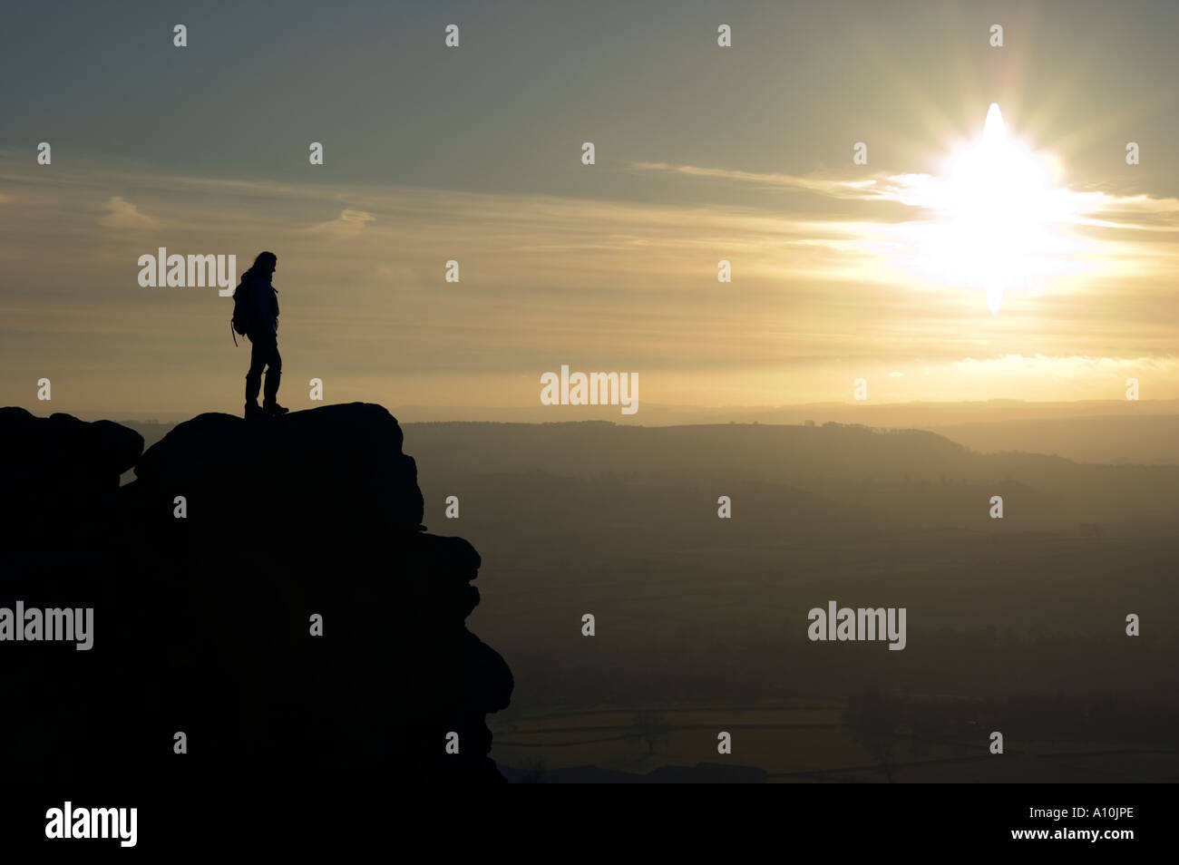 Person looking at the sunset from a crag in the Peak District National Park Derbyshire Stock Photo
