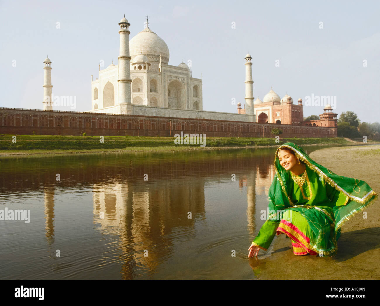 Young woman crouching on the riverbank, Taj Mahal, Agra, Uttar Pradesh, India Stock Photo