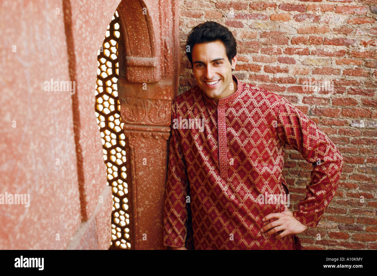 Portrait of a young man leaning against a wall and smiling Stock Photo ...