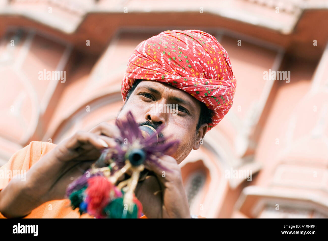 Portrait of a snake charmer playing a flute in front of a palace, Hawa Mahal, Jaipur, Rajasthan, India Stock Photo