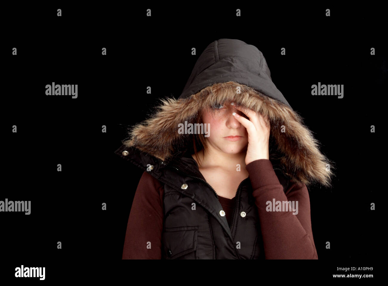 teenage girl with attitude and a fur lined hood covering face with hand Stock Photo