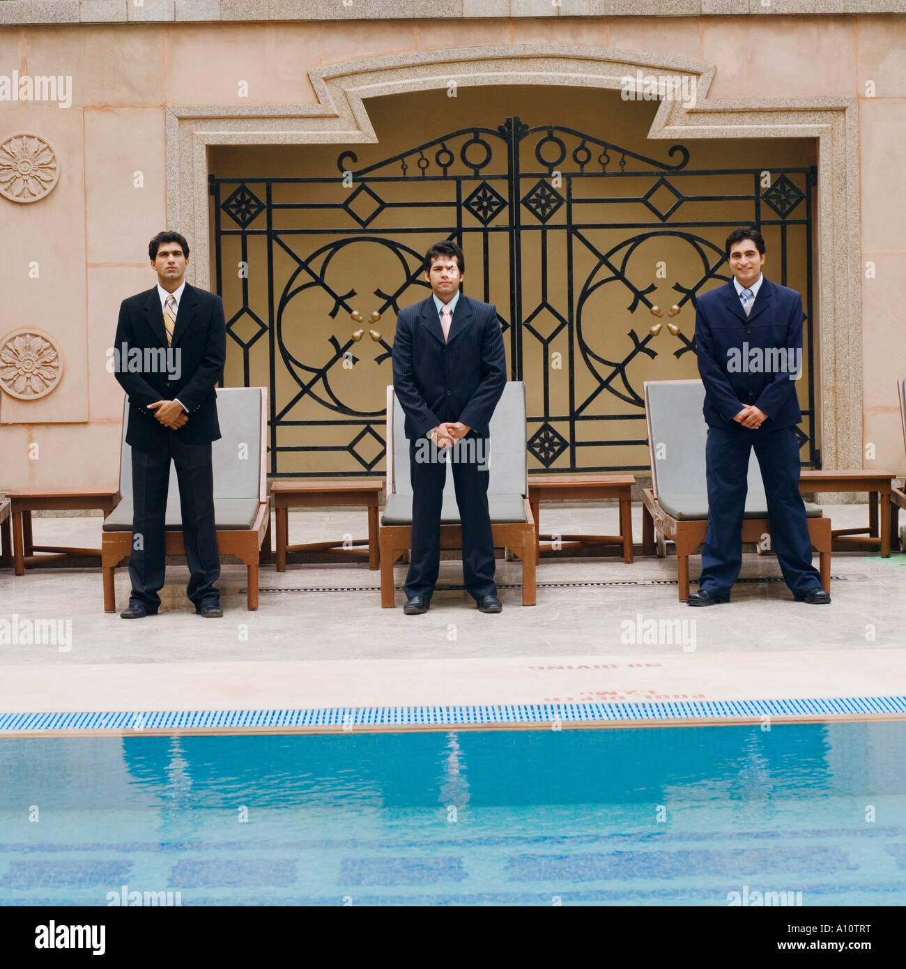 Portrait of three businessmen standing side by side near a swimming ...
