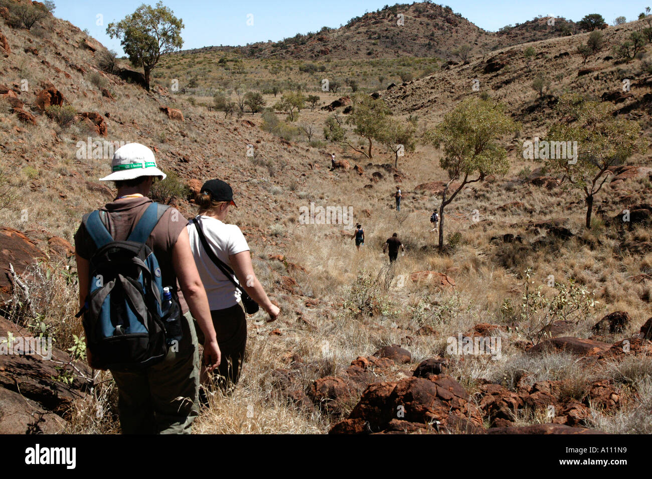 Holidaymakers trek through hills as part of an aboriginal holiday in the Red Centre Anangu Pitjantjara lands South Australia Stock Photo