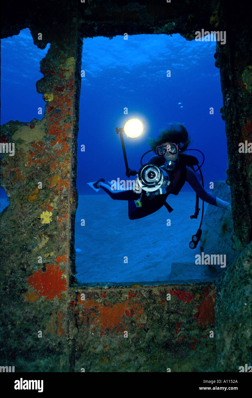 A FEMALE SCUBA DIVER AND HER VIDEO CAMERA PEER THROUGH AN OPENING IN THE WRECK OF THE BALBOA IN GRAND CAYMAN Stock Photo