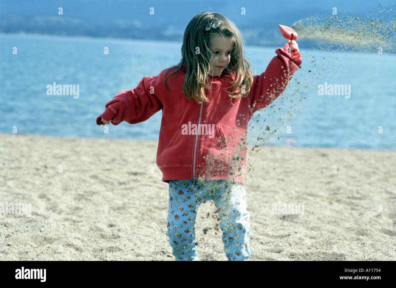 young girl throwing sand around at the beach Stock Photo Alamy