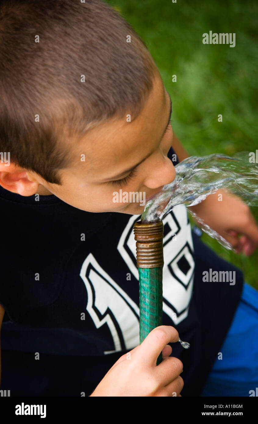 Boy drinking from garden hose Stock Photo Alamy