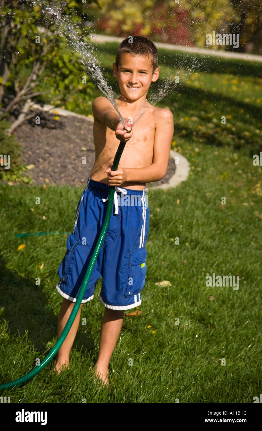 Boy spraying water from garden hose Stock Photo Alamy