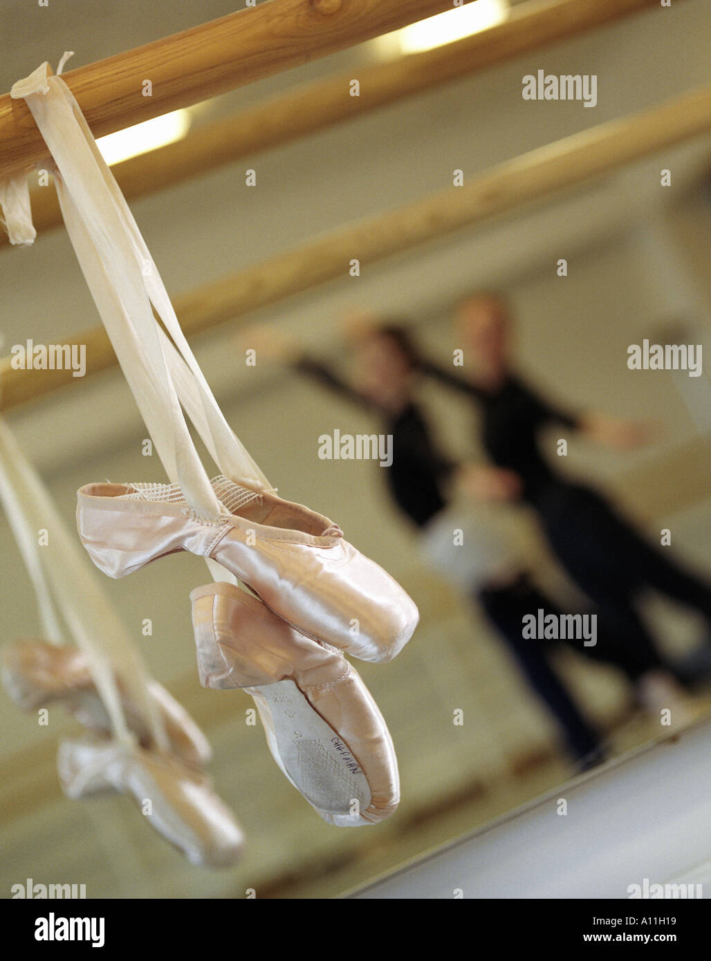 a pair of ballet shoes hanging with two ballerinas dancing in the