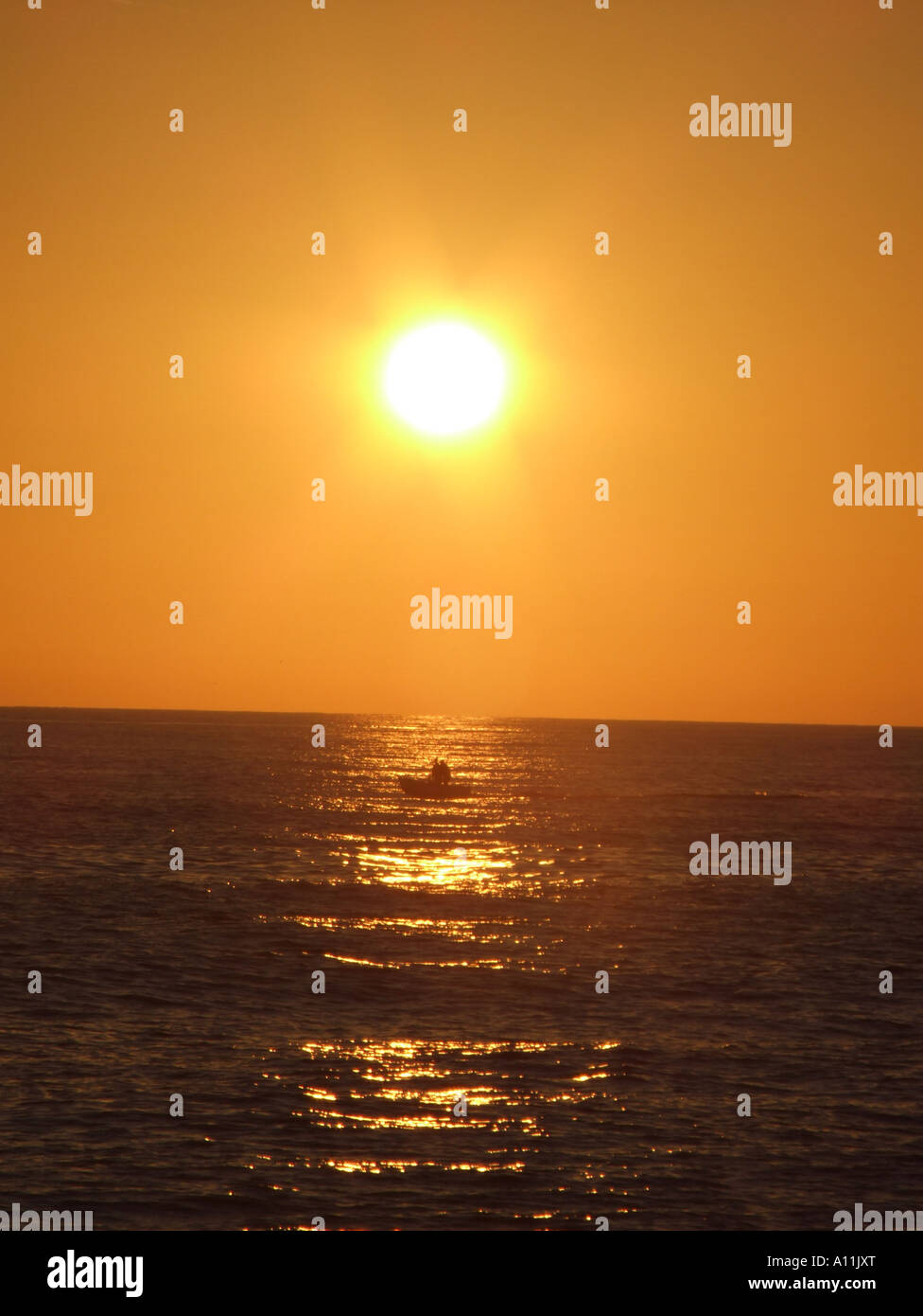 sunset over sea with fishing boat Stock Photo - Alamy