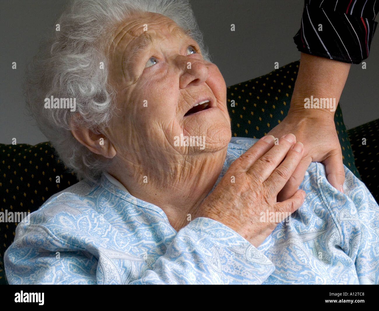 ELDERLY CARE CARER HAND COMFORT Contented smiling senior old age elderly woman looks up and touches comforting hand of carer Stock Photo