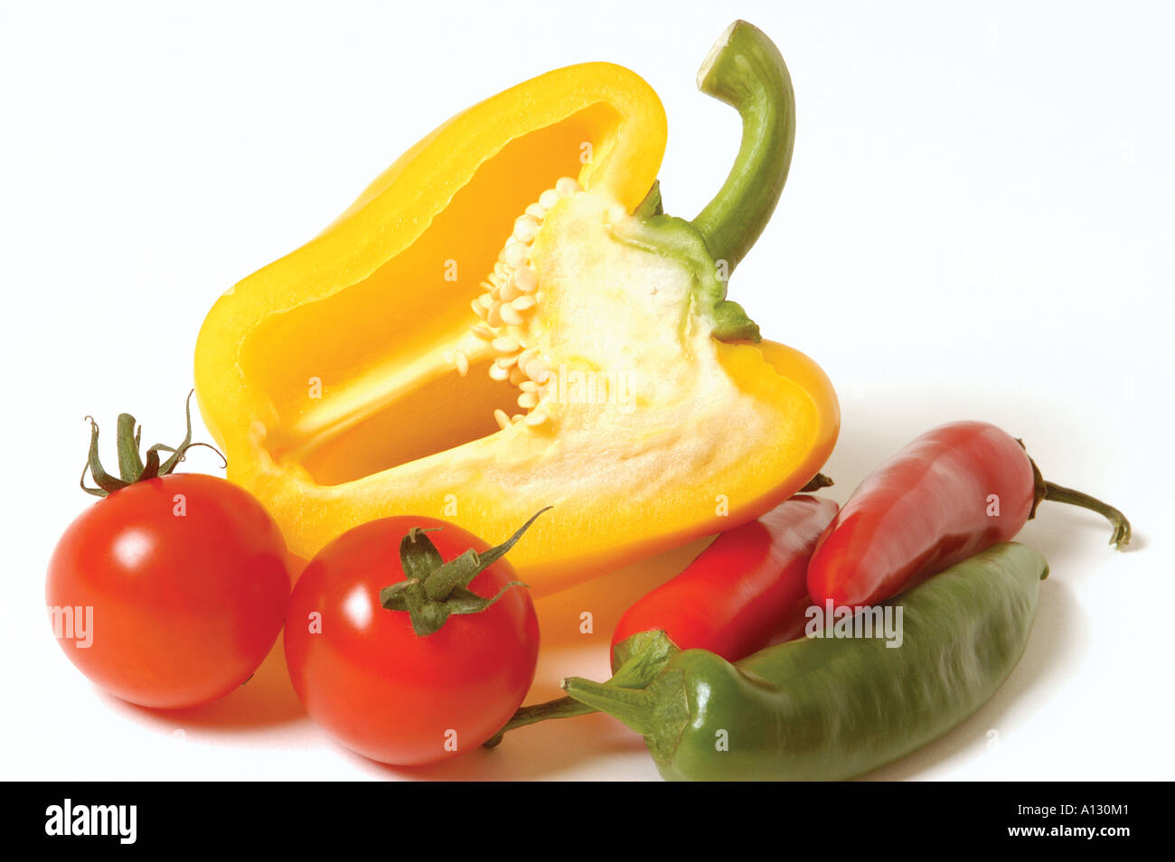 Close up of Tomatoes with a Yellow bell Pepper capsicum and Red and Green Chillies chilies on white background Stock Photo