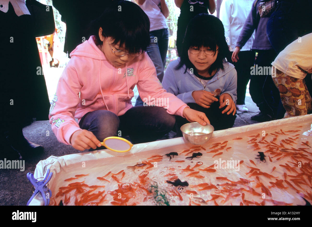Two sisters play a traditional Japanese carnival game of catch the goldfish in Maruyama Park