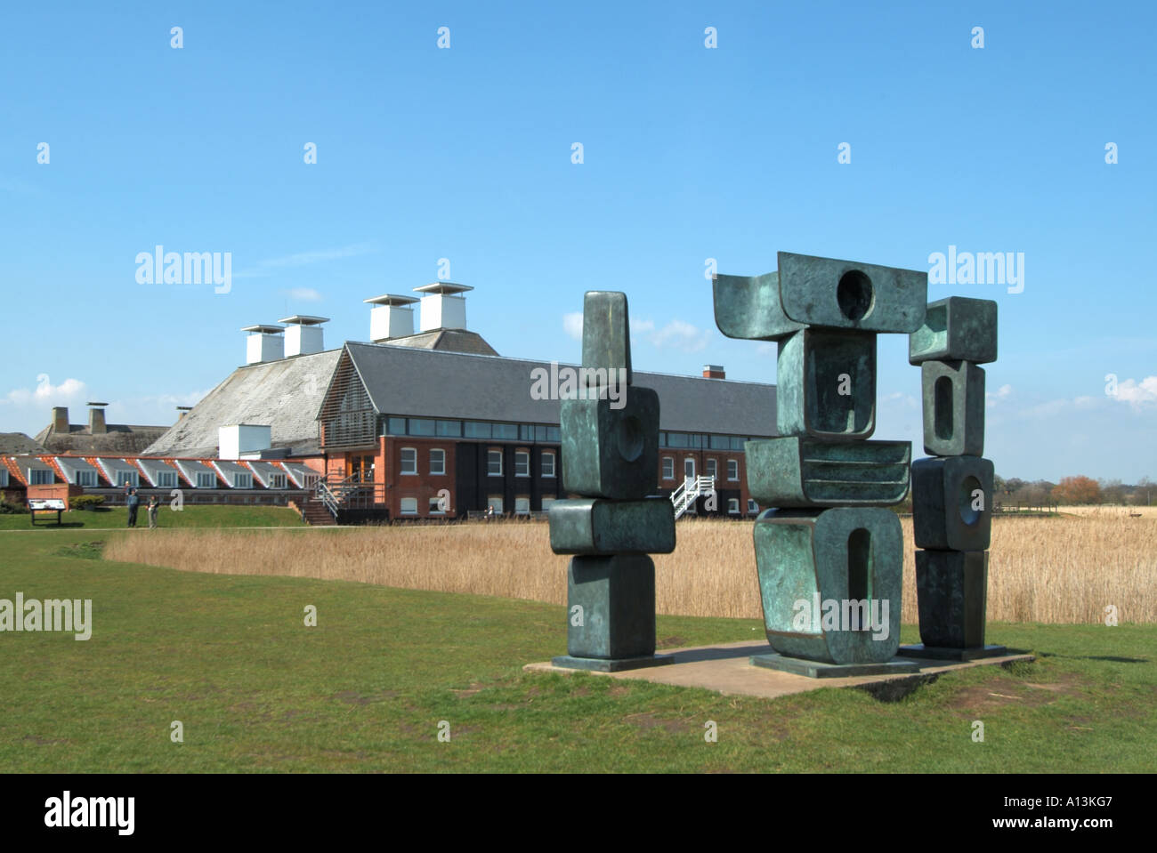Snape Maltings Barbara Hepworth Family of Man sculpture in landscape converted theatre concert hall buildings beyond Suffolk East Anglia England UK Stock Photo
