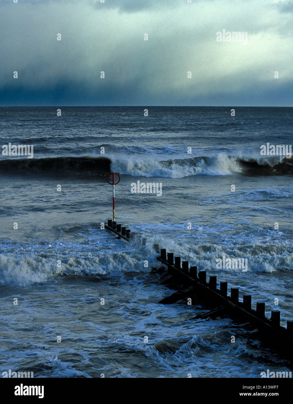 A portrait image of moody Aberdeen beach North sea with a wooden groin extending into the stormy sea waves. Stock Photo