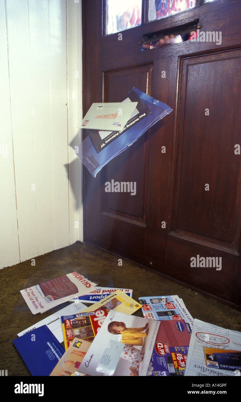 Junk mail being pushed through a letterbox of a house in England UK Stock Photo
