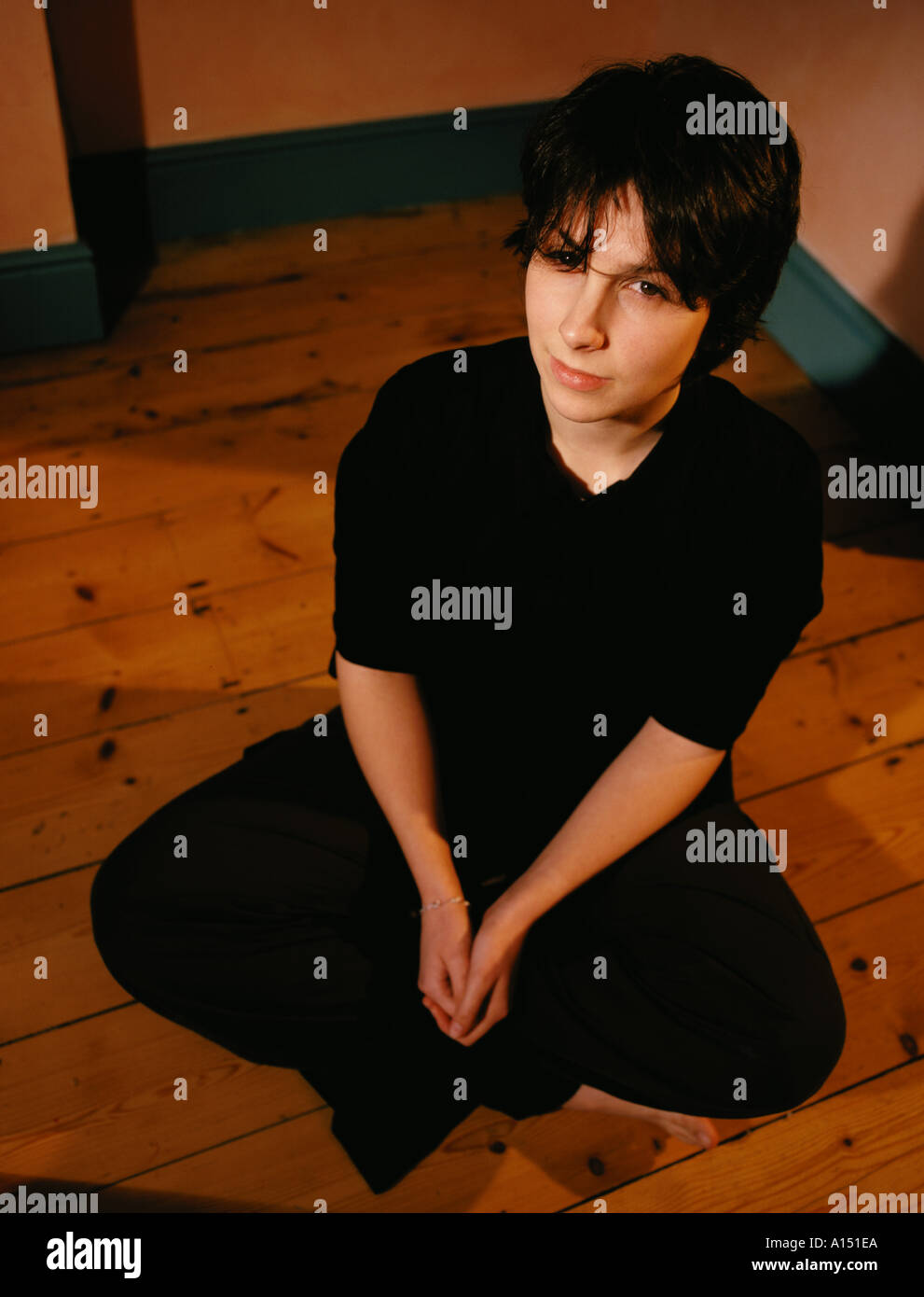 Teenage girl sitting cross legged on floor wearing black clothes Stock ...