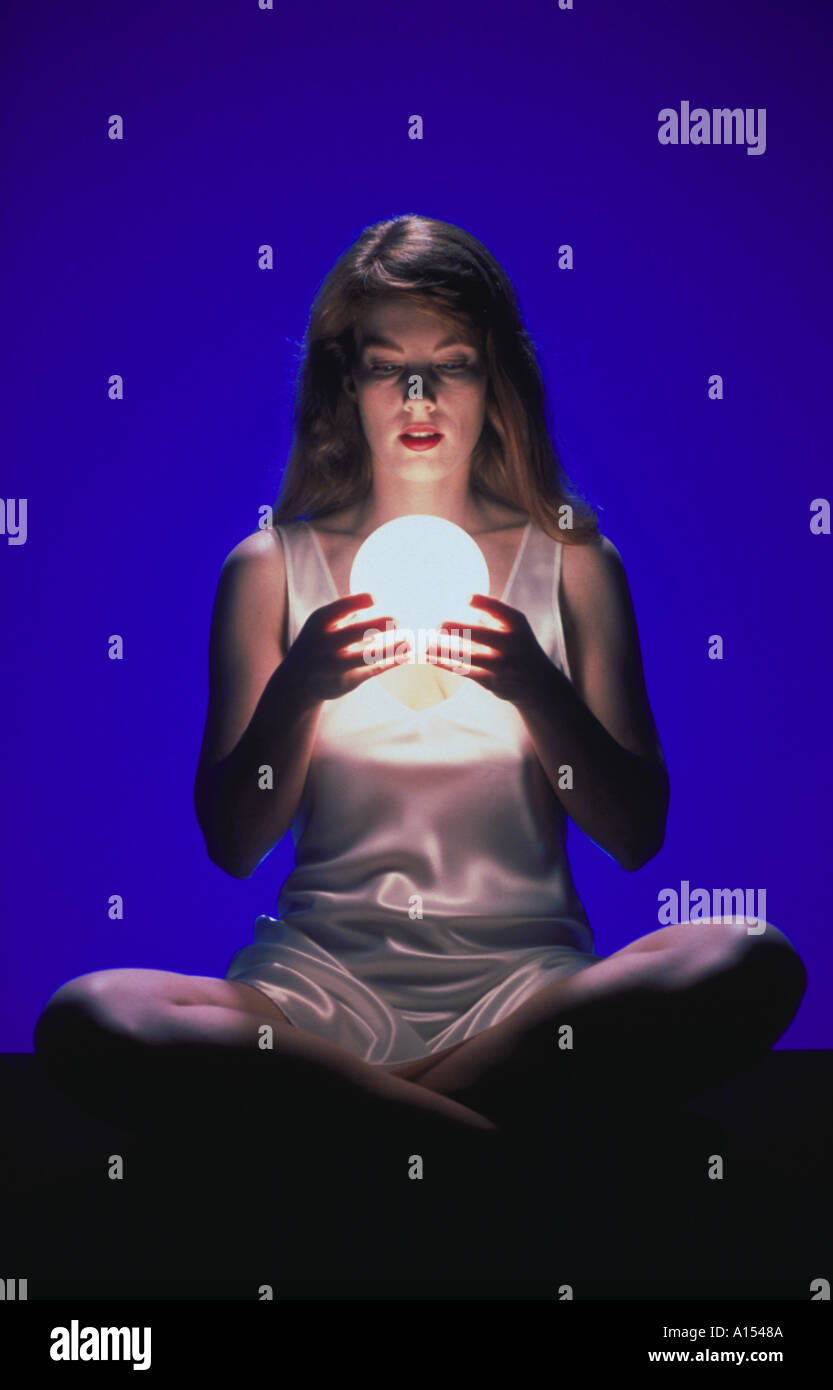 A woman sitting and holding a glowing globe in her hands Stock Photo