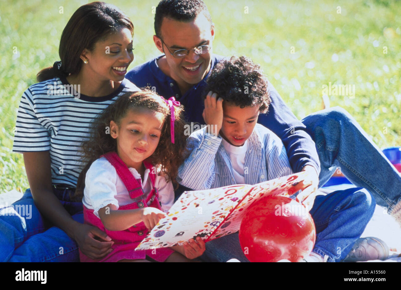 An African American family sitting outside reading together Stock Photo