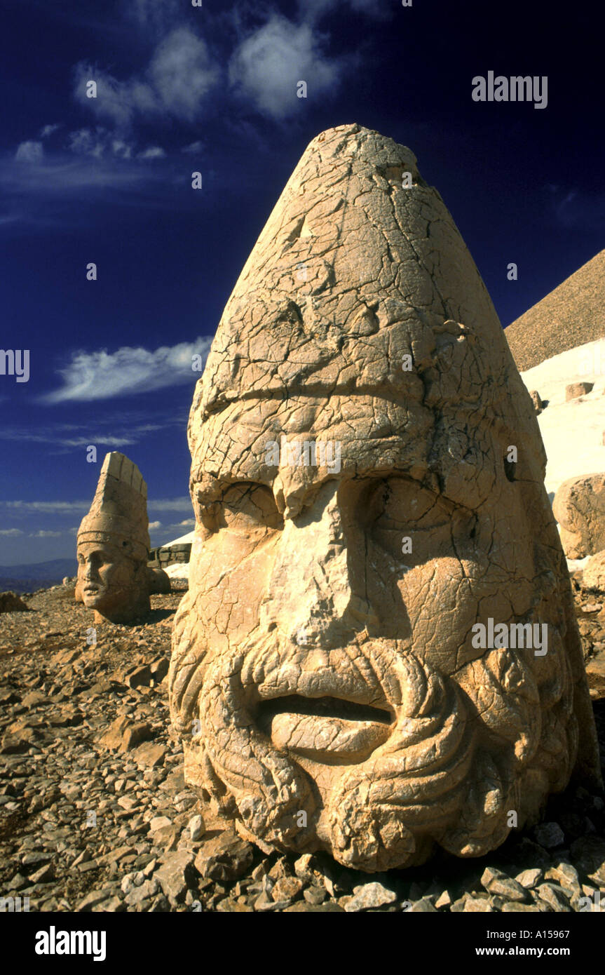 Statue head portraying Zeus and Antiochos in background on the west terrace at Namrut Dag Turkey A Woolfitt Stock Photo