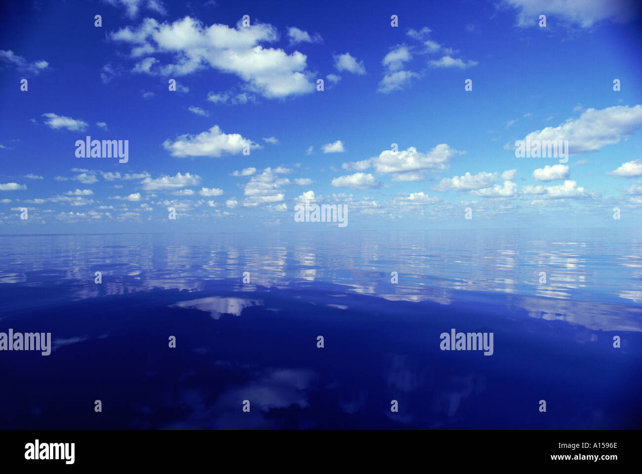 Reflections of white clouds and blue sky in the water of the Indian ...