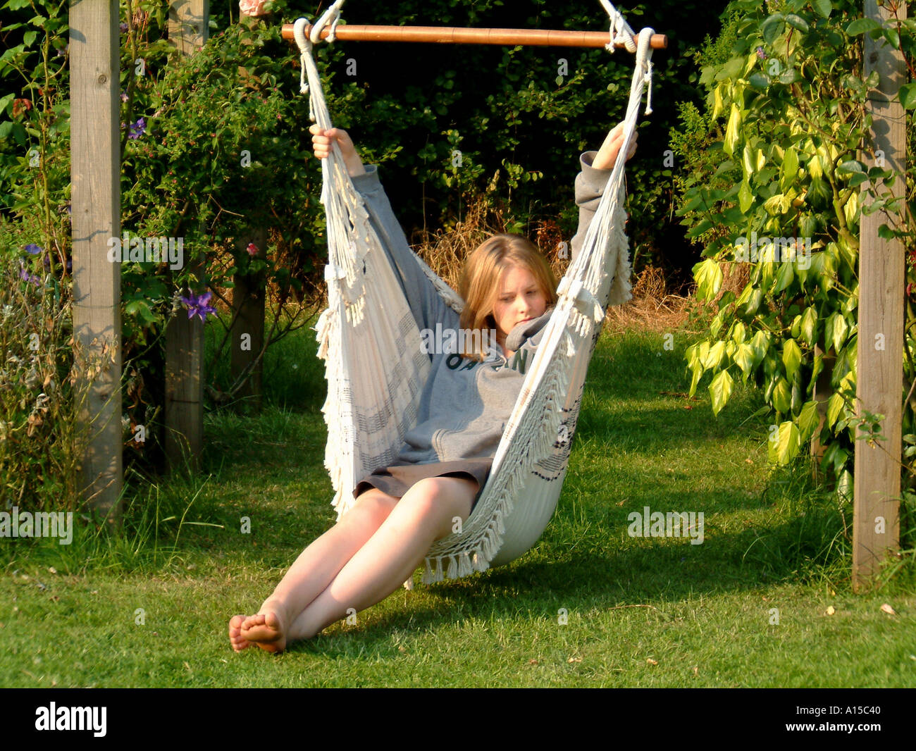 Young woman relaxing in rope hammock chair in sunny summer garden ...