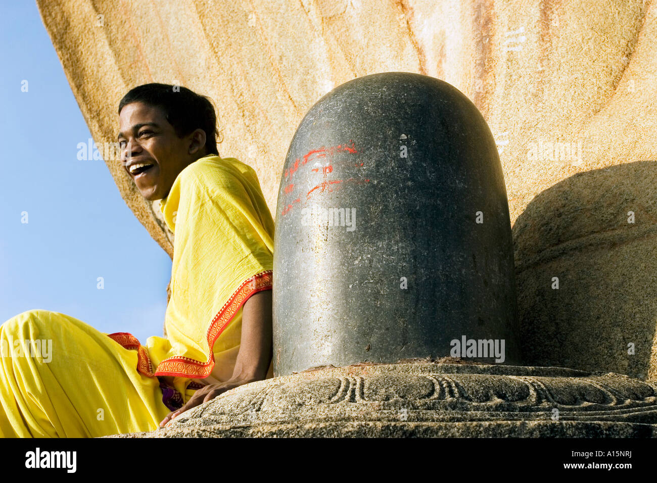 Young Brahmacharya Indian boy laughing sat next to the shiva lingam at  Veerabhadra Temple, Lepakshi, Andhra Pradesh, South India Stock Photo