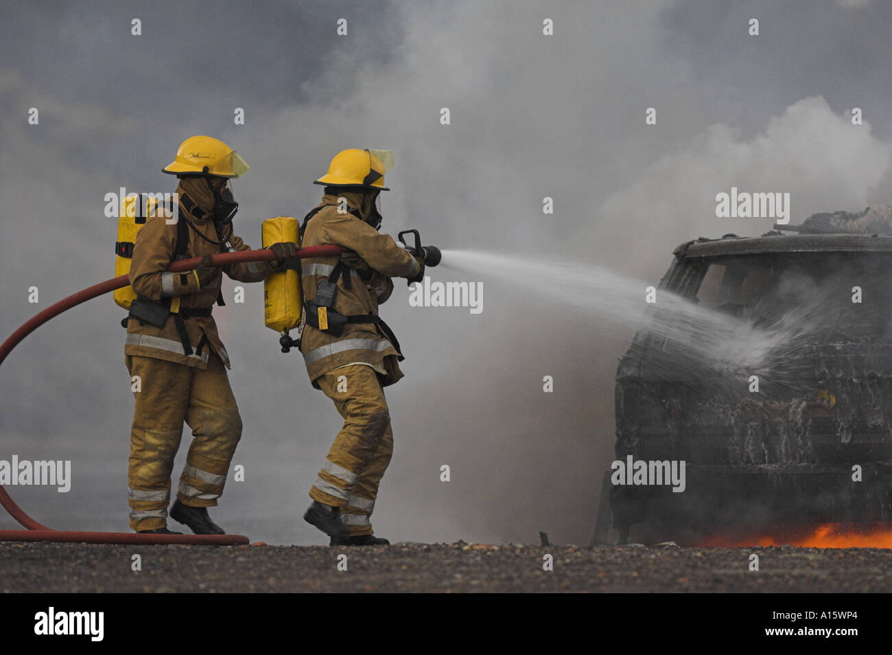Two firefighters tackling a burning car. Stock Photo