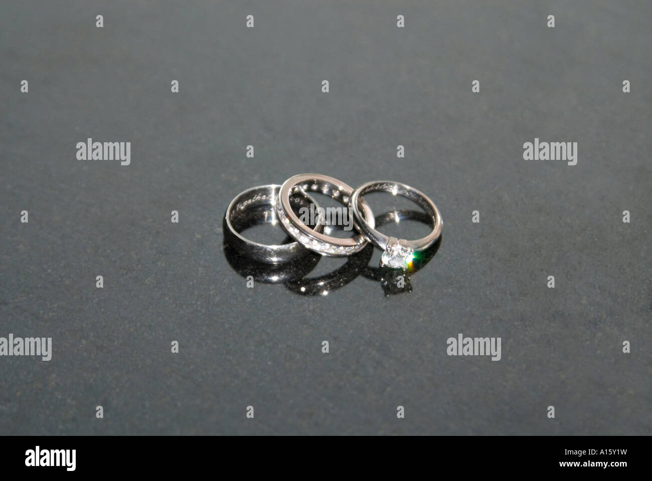 Horizontal close up of the Bride and Groom's platinum wedding bands and bride's diamond engagement ring on a black background. Stock Photo