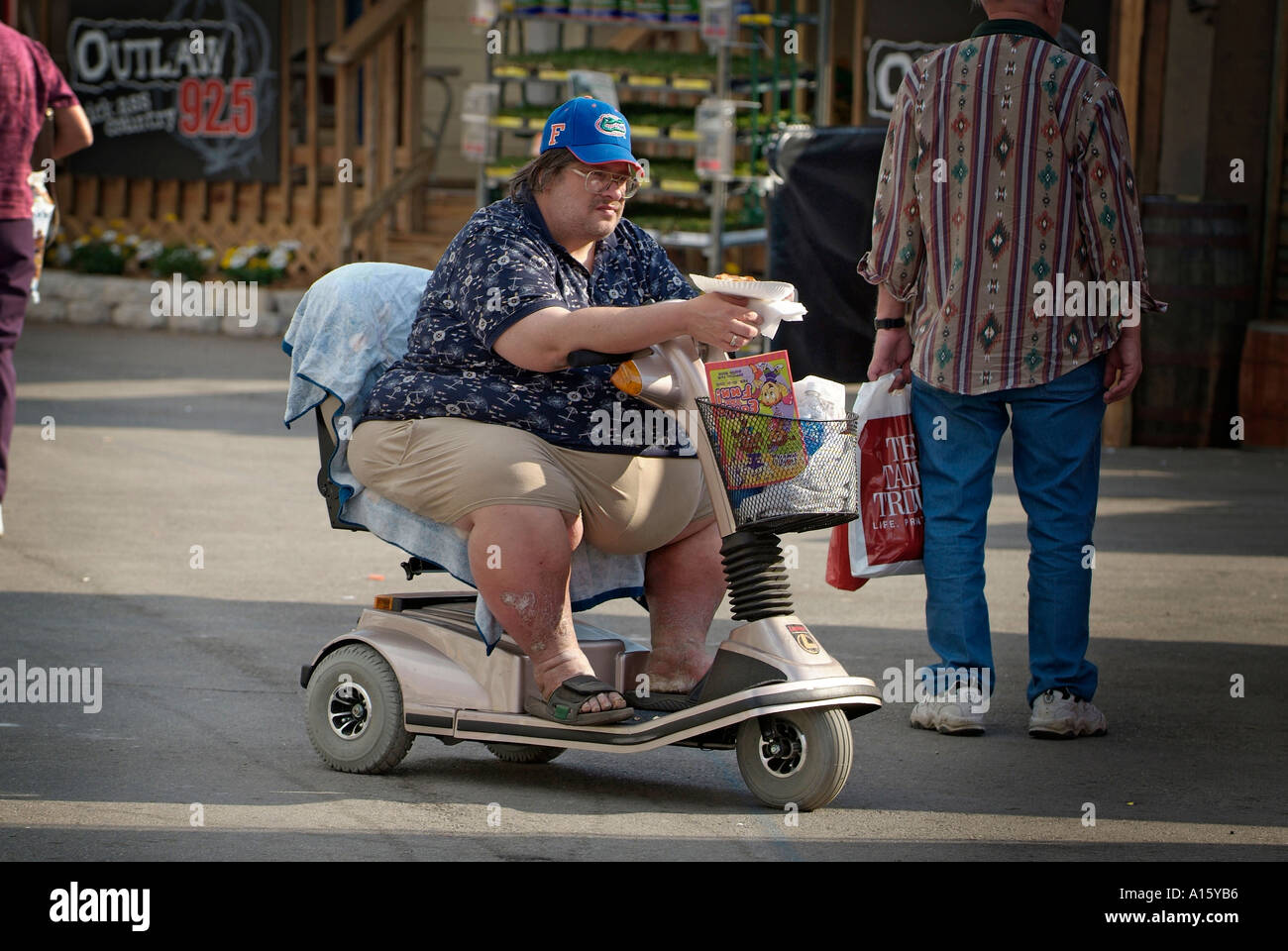 Overweight male on motorized wheel chair eats food Stock Photo