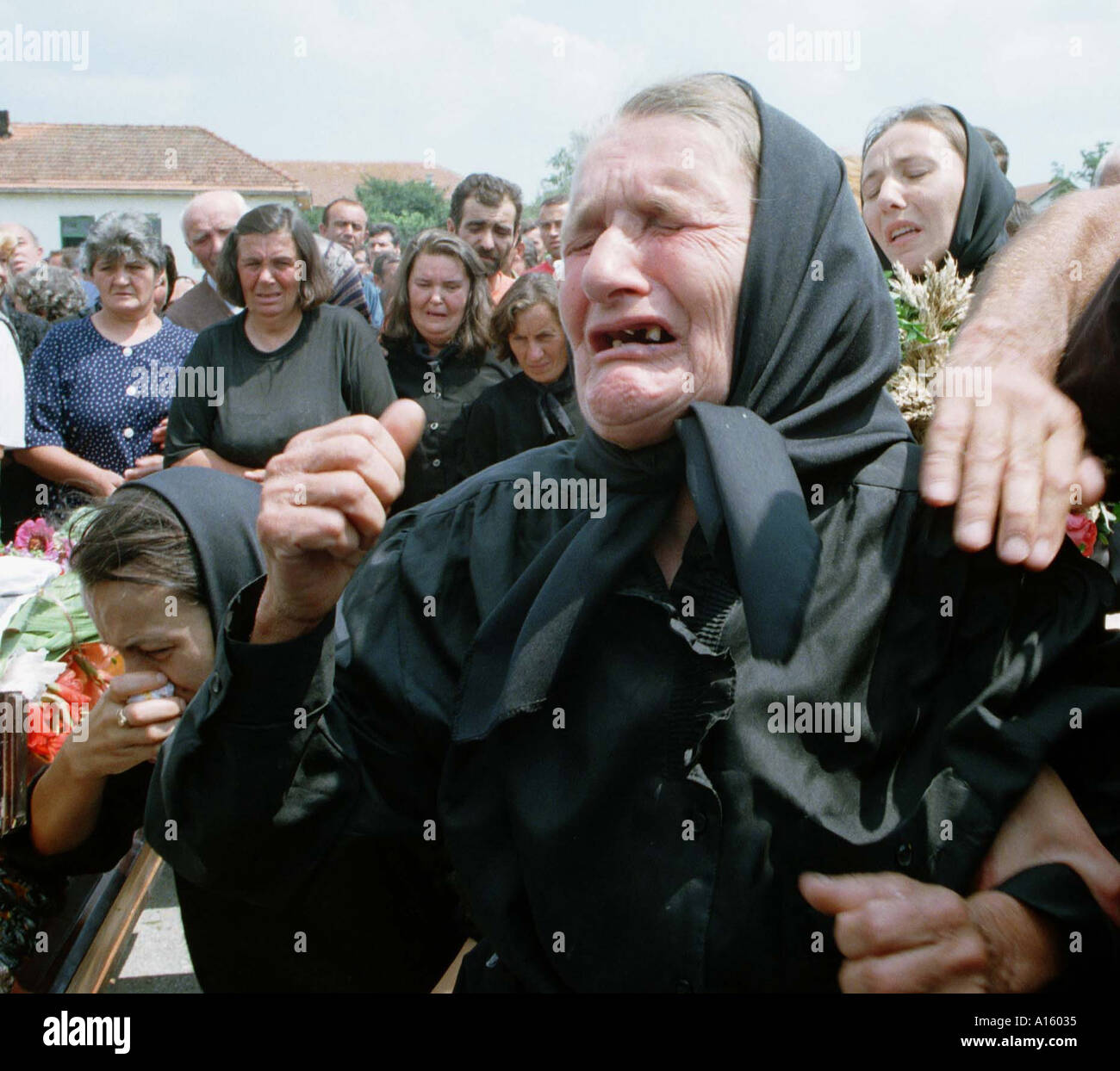 A Serbian woman cries over the body of a slain family member during a funeral Wednesday July 28 1999 for the fourteen Serbs Stock Photo