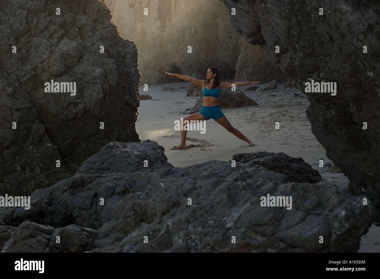 Young woman practicing yoga on beach between rocks Stock Photo Alamy