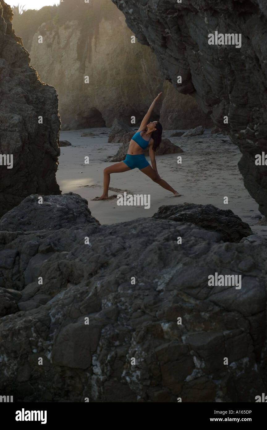 Young woman practicing yoga on beach between rocks Stock Photo Alamy