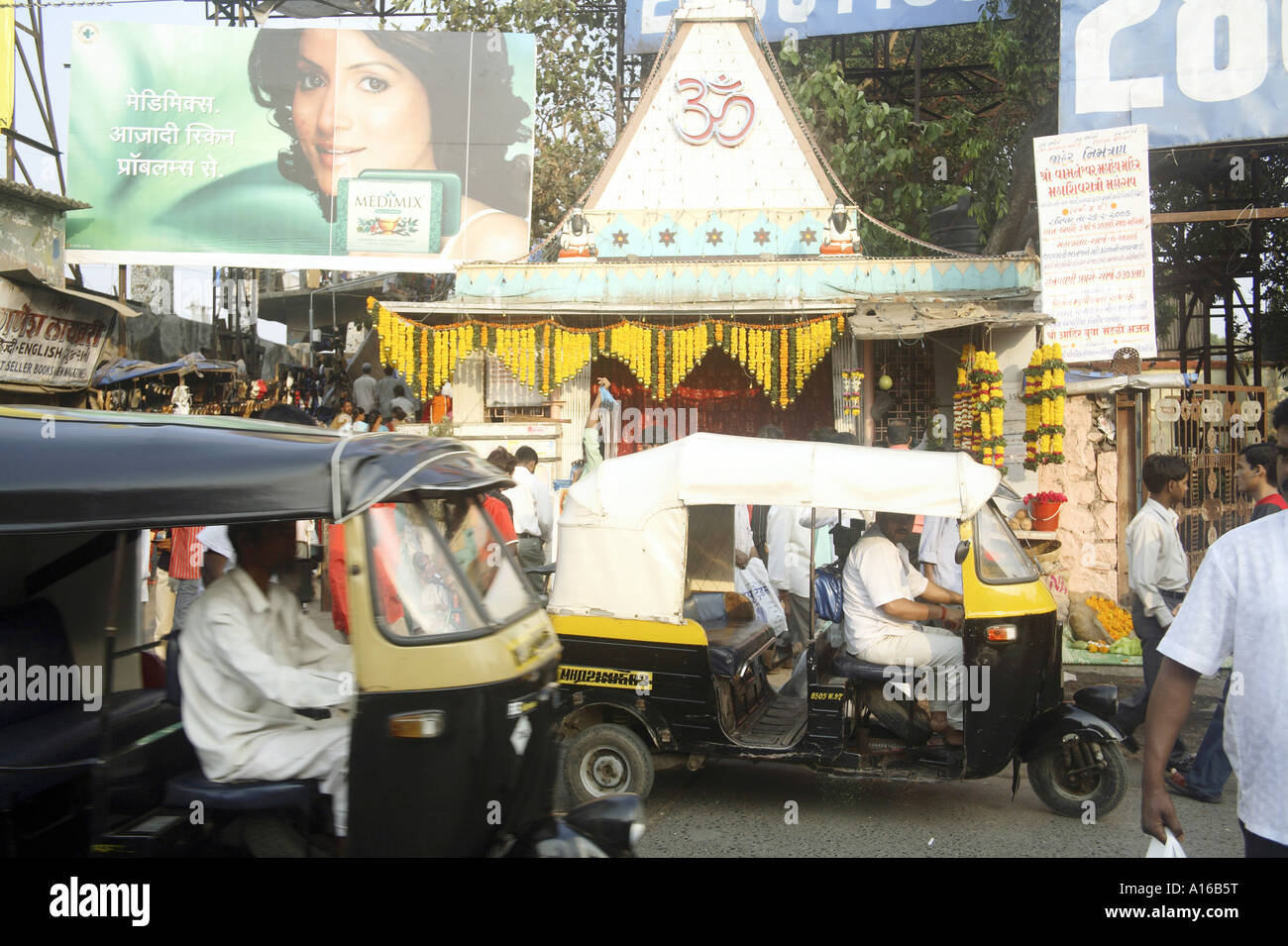 Indian street Hindu temple with OM written surrounded by modern hoardings and auto taxi at Borivali Bombay Mumbai India Stock Photo