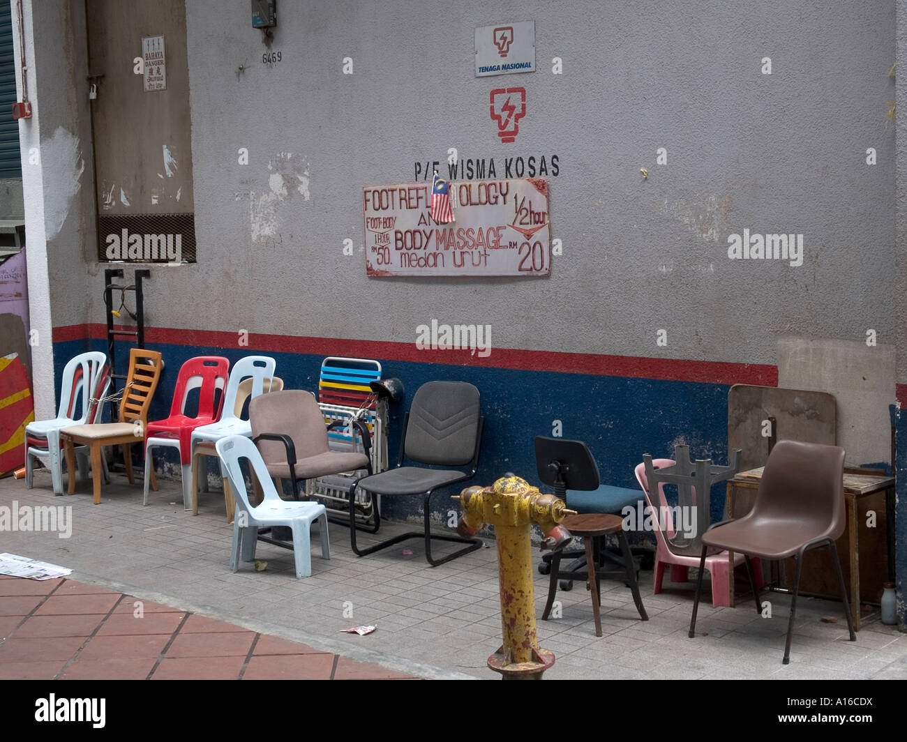 A row of empty chairs below a foot massage vendor sign in Kuala Lumpur