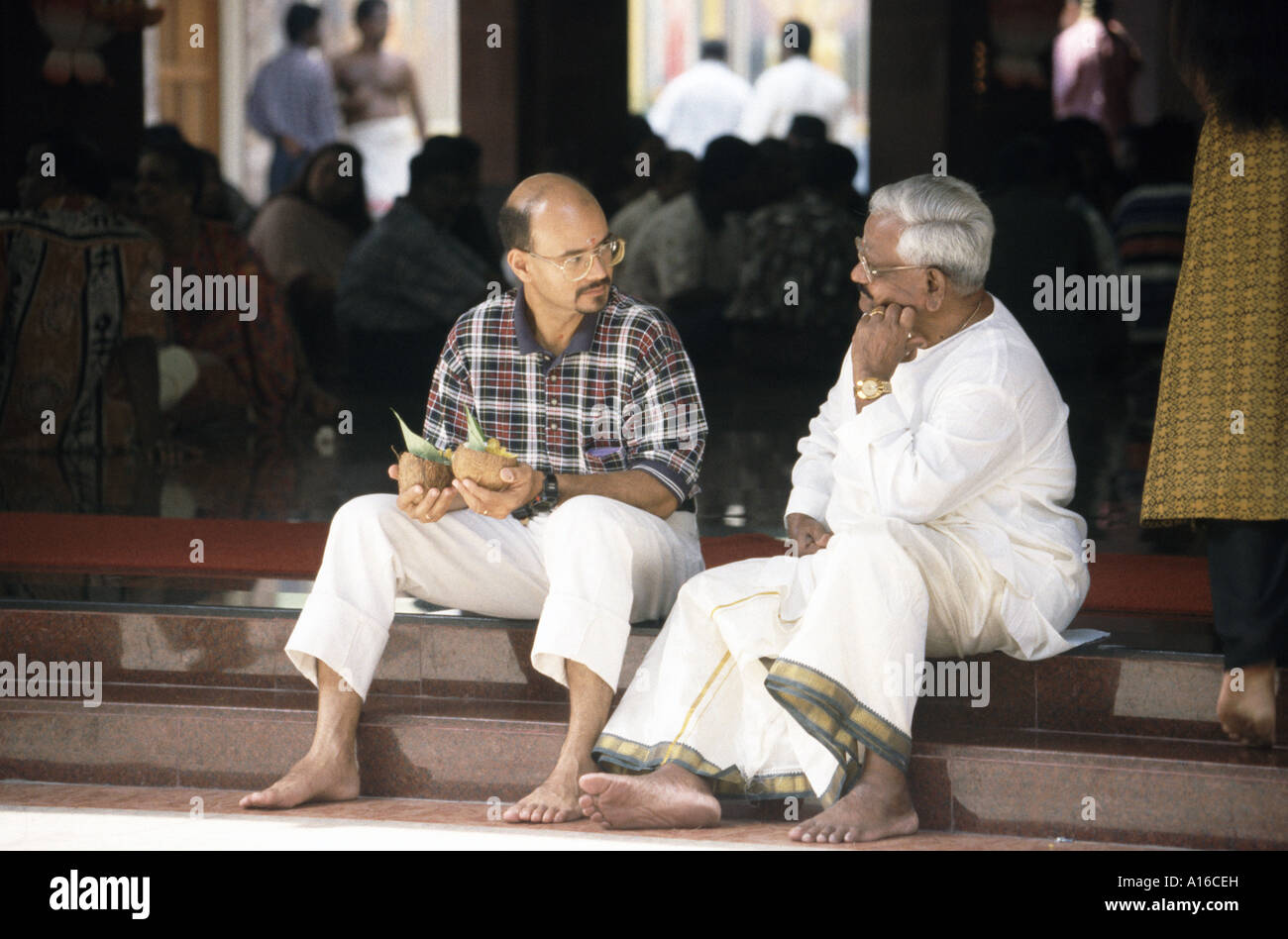 Two Hindu men sit chatting in the Sri Mariamman Hindu temple in Chinatown Kuala Lumpur Malaysia Stock Photo