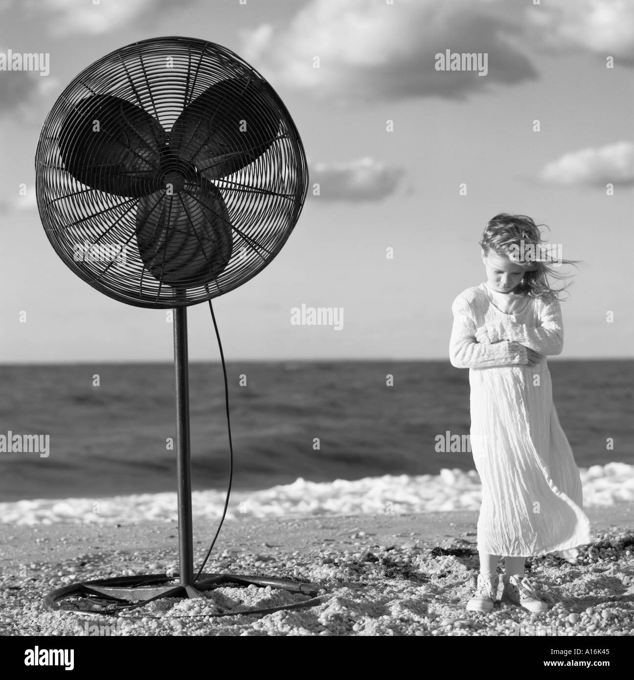 Little girl standing next to big fan. 7, 8, 9, 10, 11 12 years old Stock Photo
