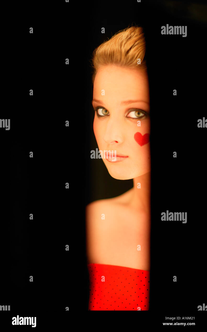 Portrait of young woman 18, 19, 20, 21, 20-24, 24-29, 30-34, years old with red heart painted on her cheek Stock Photo