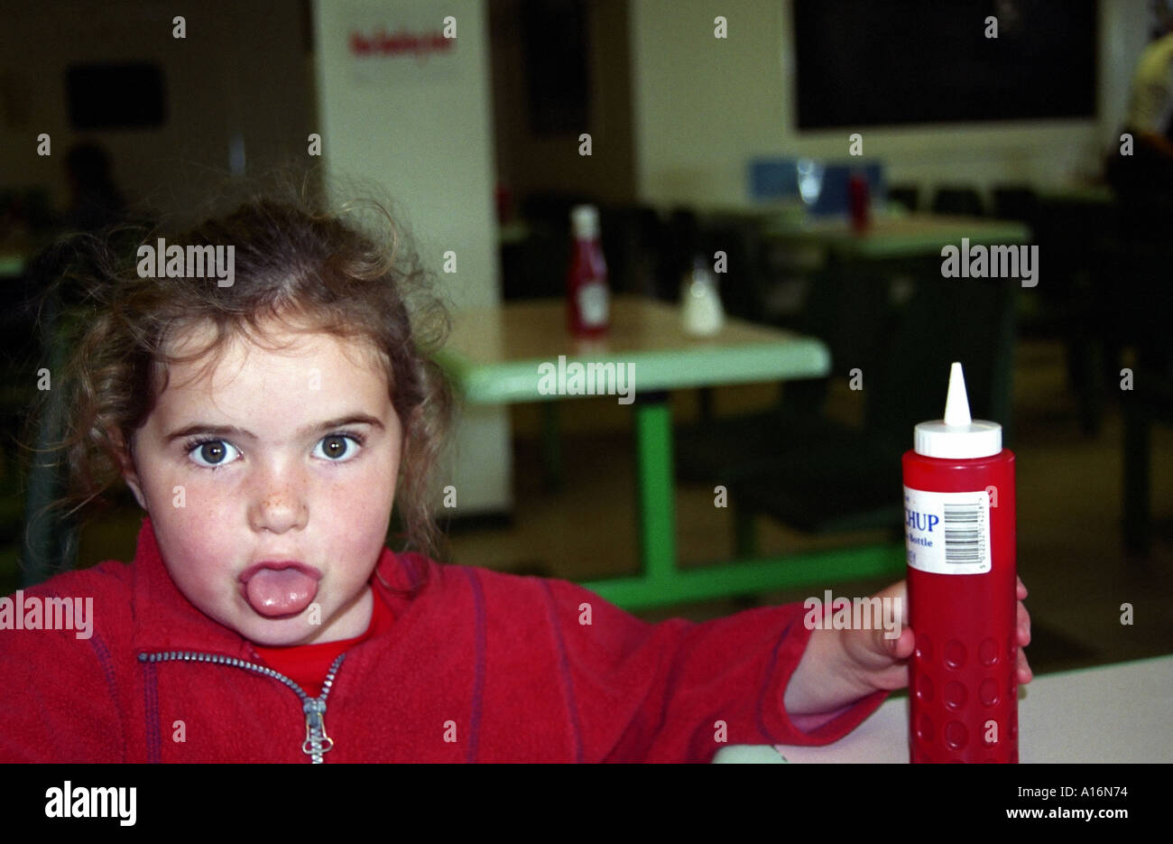 A young girl reaches for the ketchup in a cafe Stock Photo Alamy