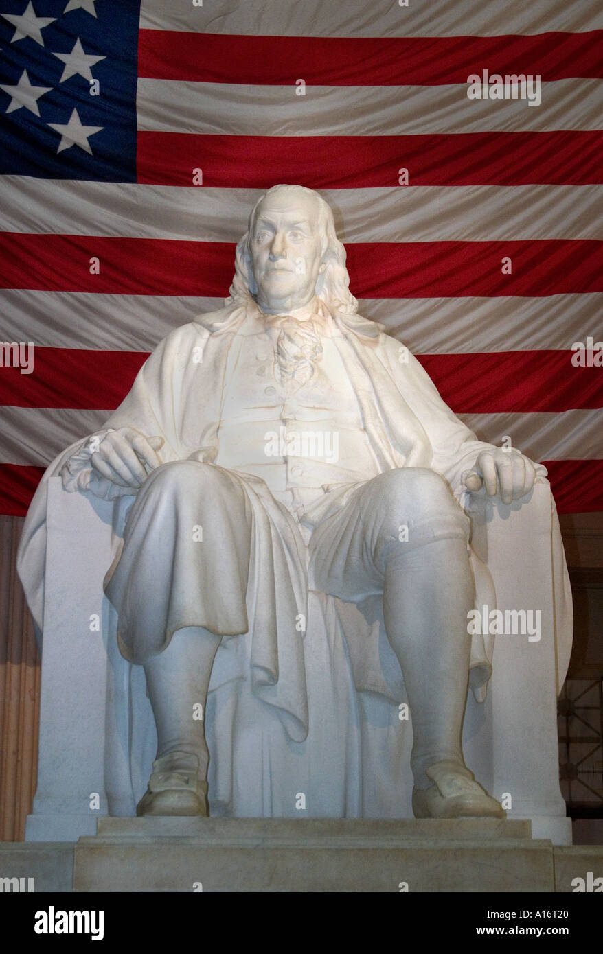 statue of Benjamin Franklin sitting in front of large American Flag at the Ben Franklin Children s Museum Stock Photo