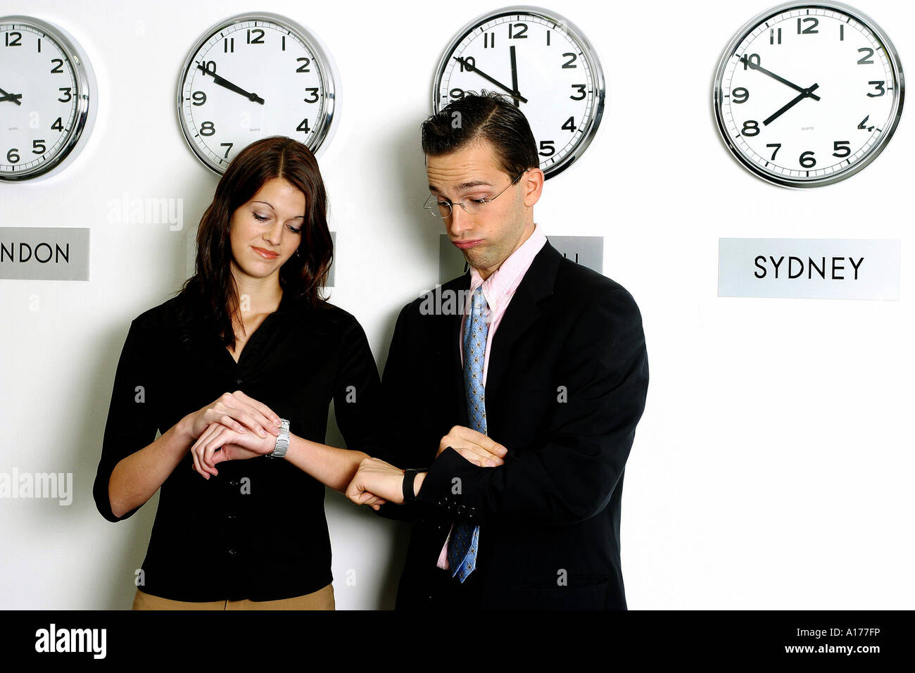 Man and woman in front of different world time clocks Stock Photo