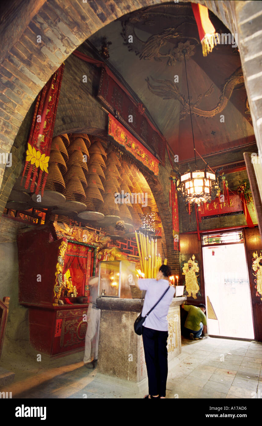 Altar spiral incense and lady burning incense sticks in a Hong Kong