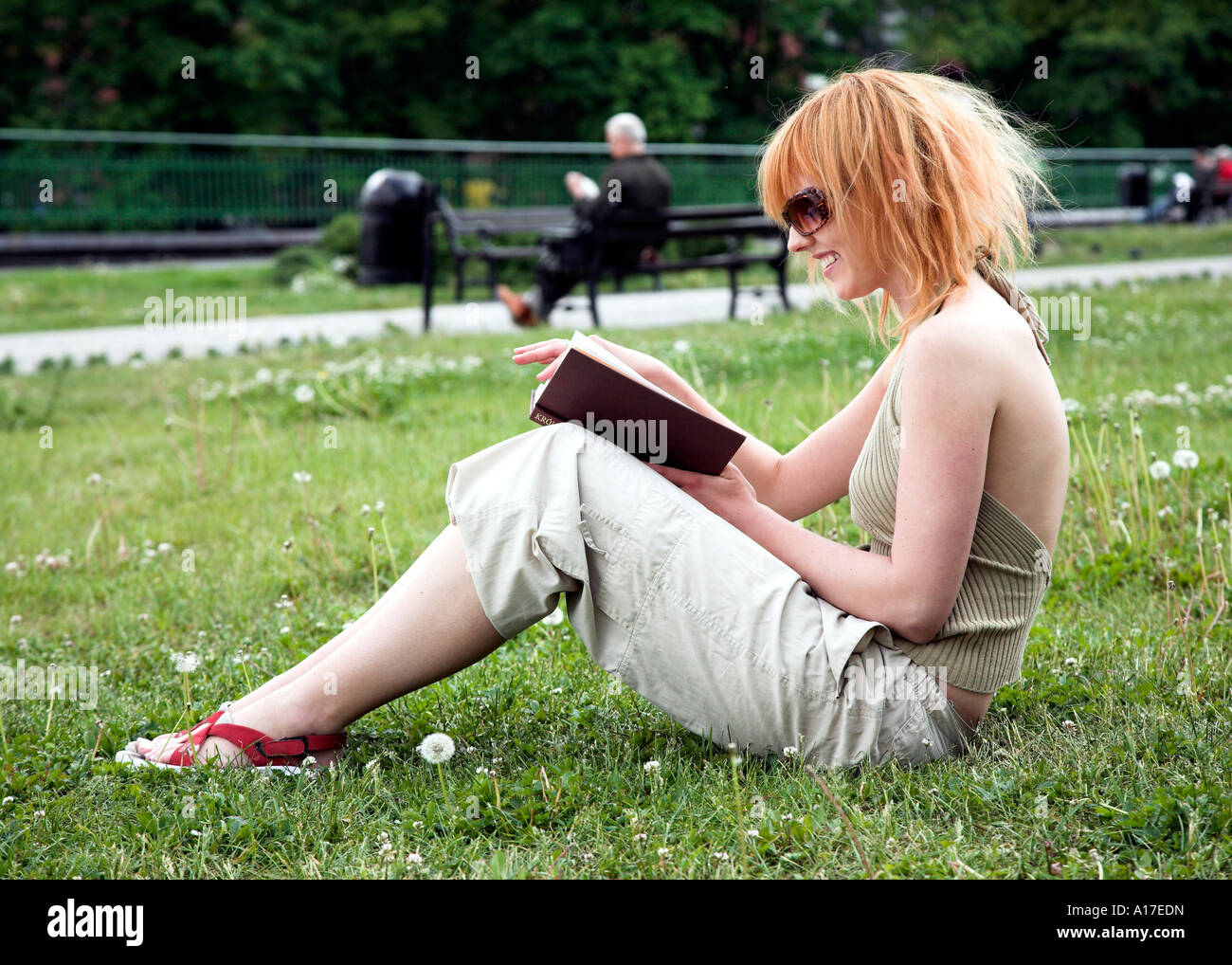 Woman sitting in a park and reading a book Stock Photo - Alamy