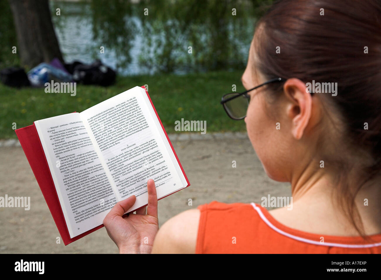 Woman sitting in a park and reading a book Stock Photo - Alamy