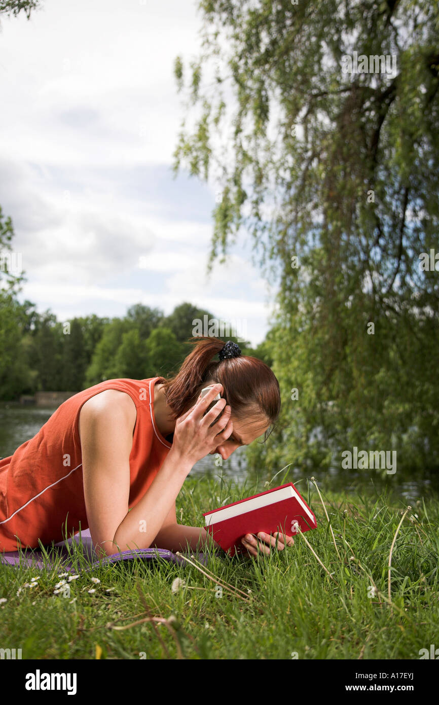 Woman sitting in a park and reading a book Stock Photo - Alamy