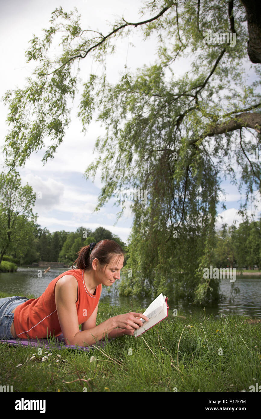Woman sitting in a park and reading a book Stock Photo - Alamy